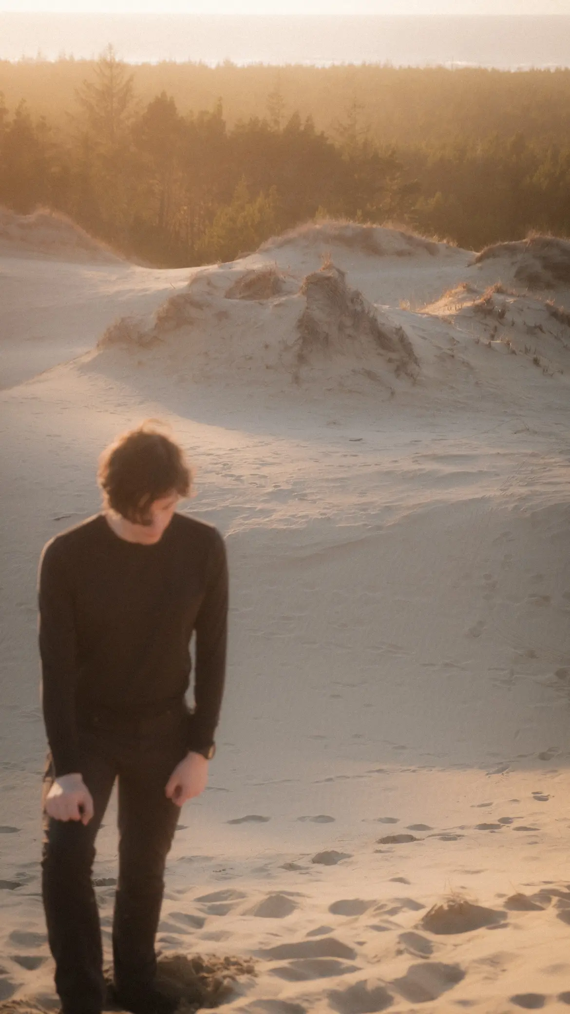 person climbing up sand dune near sunset