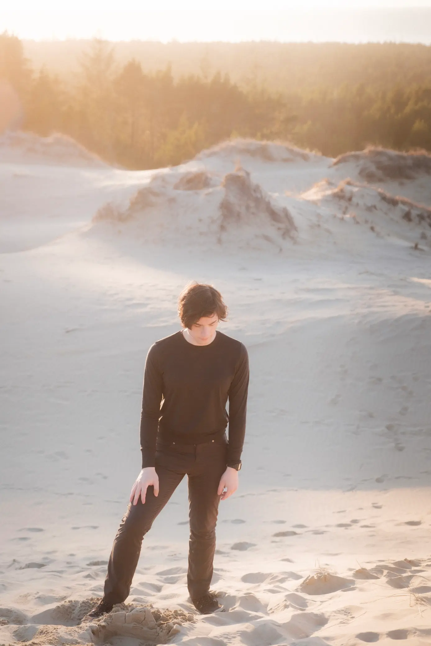 person climbing up sand dune near sunset again