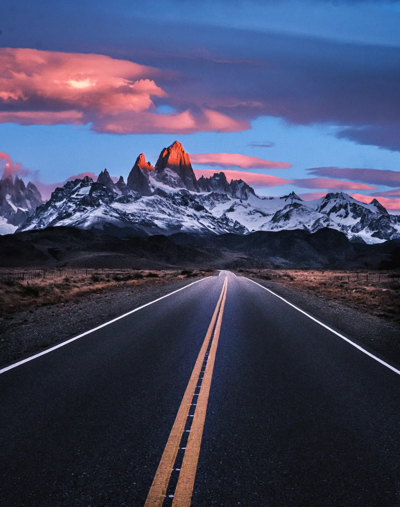 A Road leads into the mountains under an orange sunrise