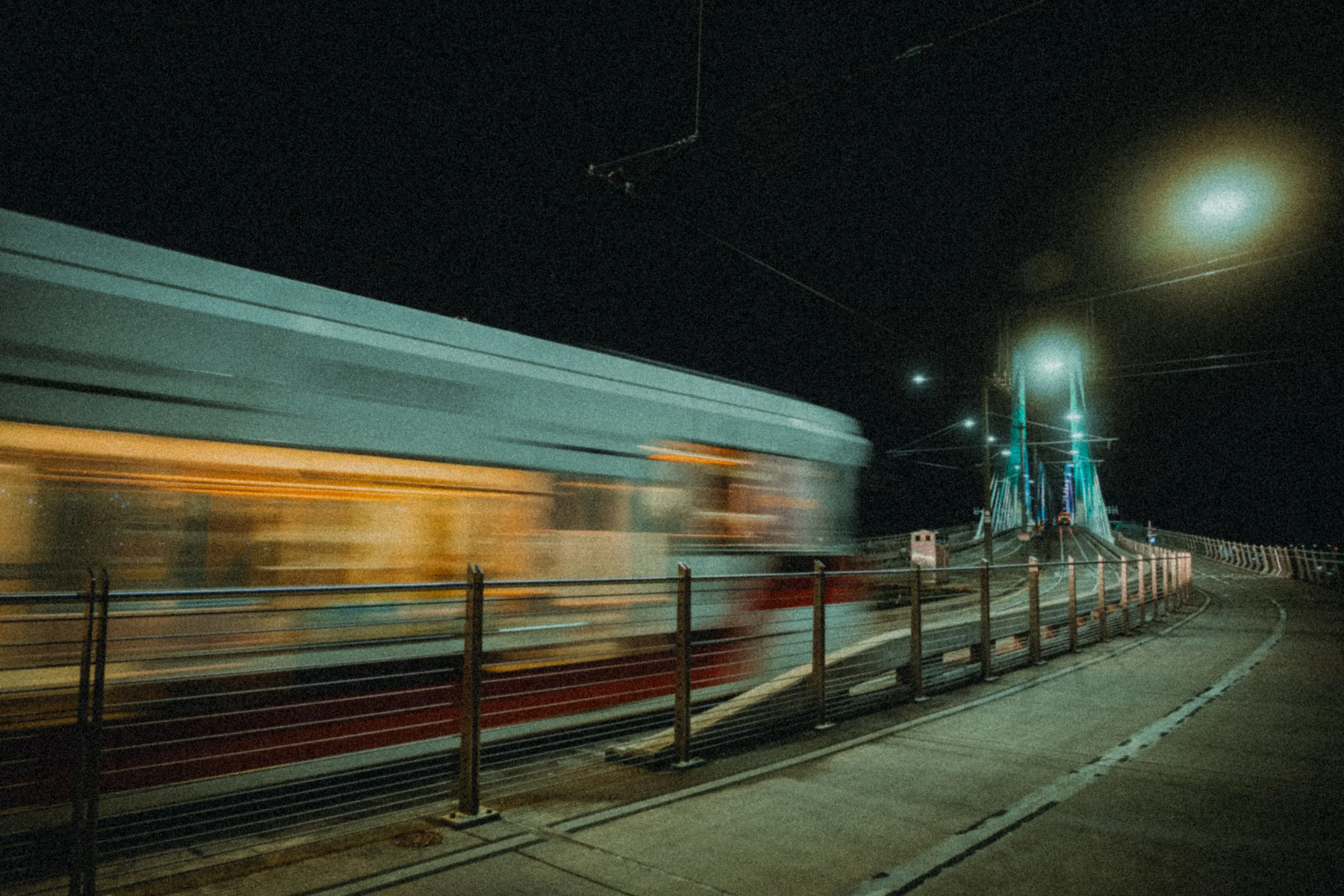 a blurred train moves across a bridge at night