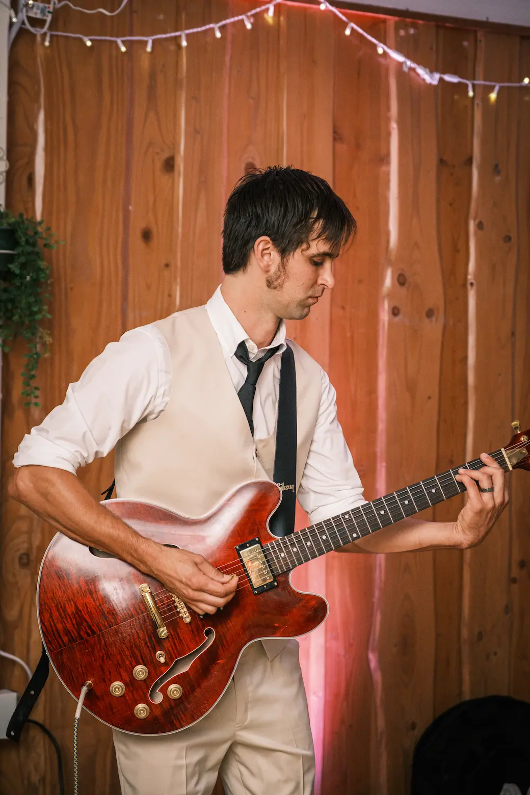 A person plays a red electric guitar at a wedding reception