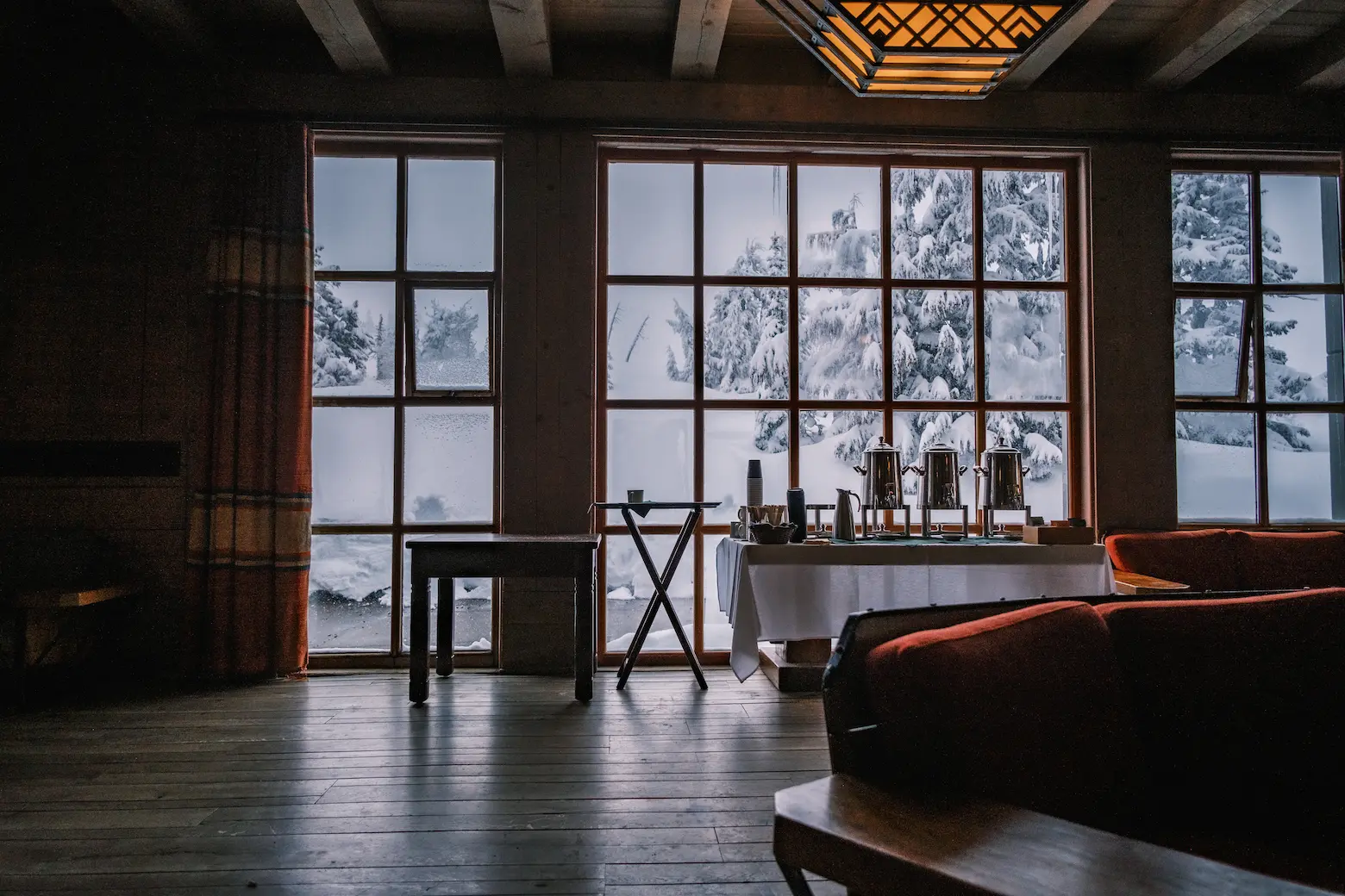 View of snow covered trees outside the windows, with a coffee station and wooden furnishings