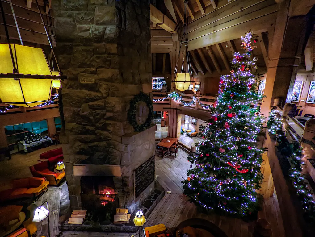 view of the Timberline Lodge Headhouse, from the second story balcony overlooking a Christmas tree and fireplace in the winter in the evening